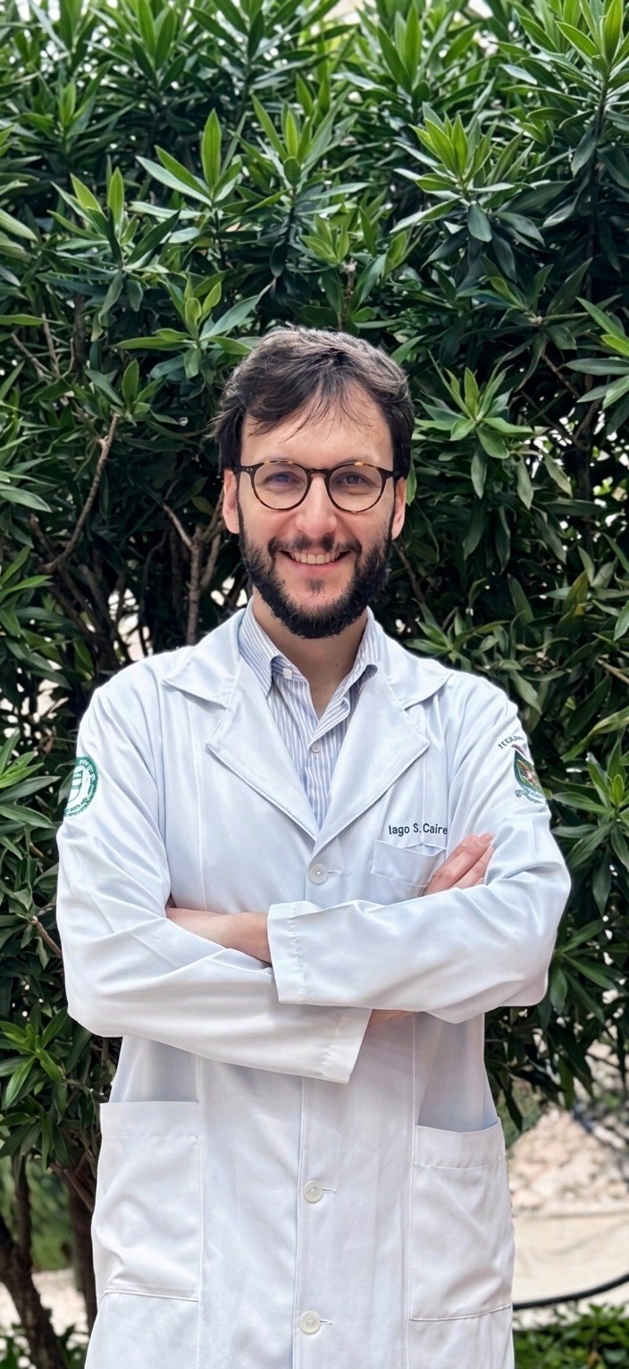 Iago Caires de jaleco, em um ambiente externo.